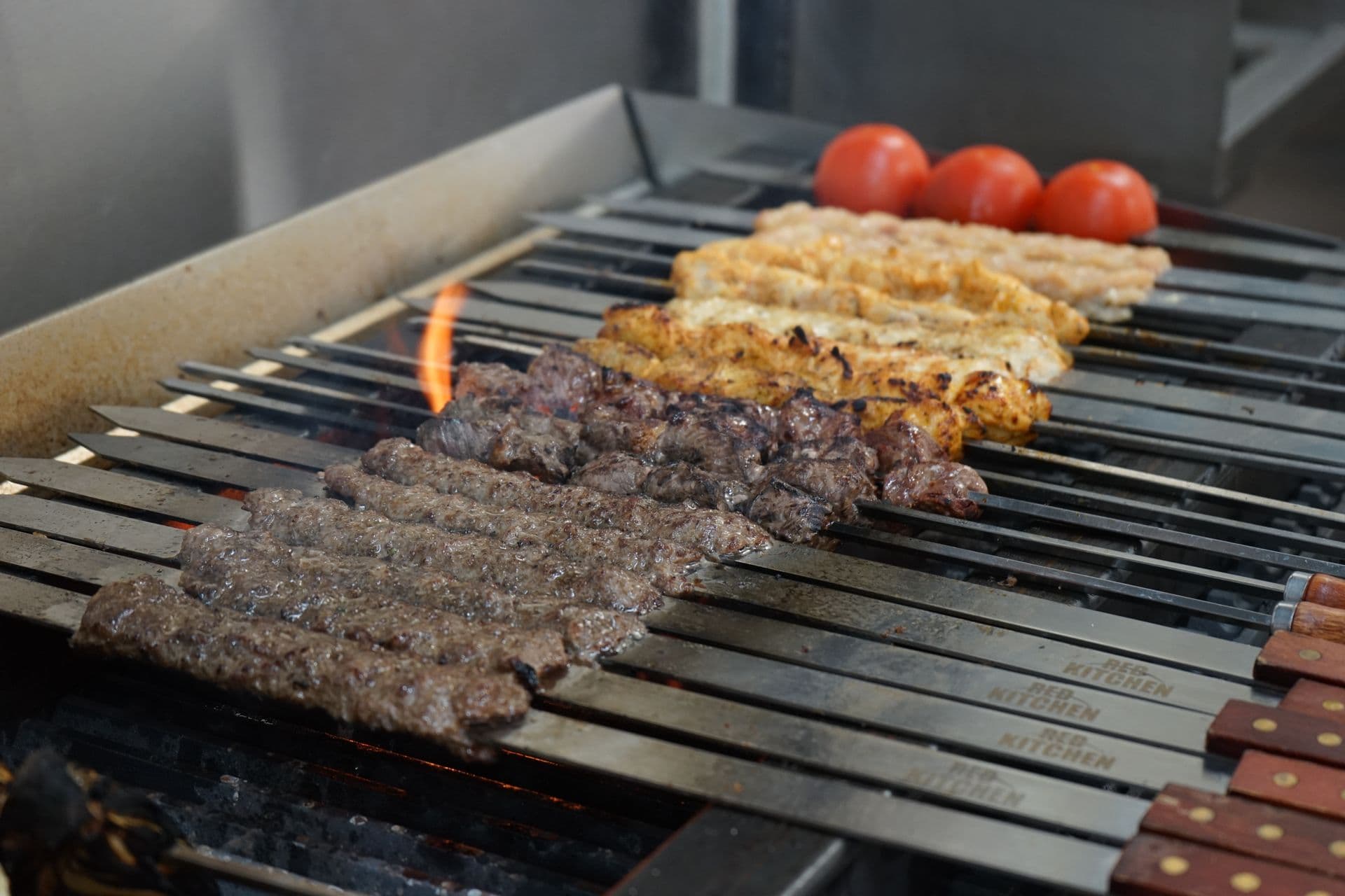Iraqi beef kabob, beef tikka and chicken tawook skewers cooking over a charcoal grill at Babylon Kabob