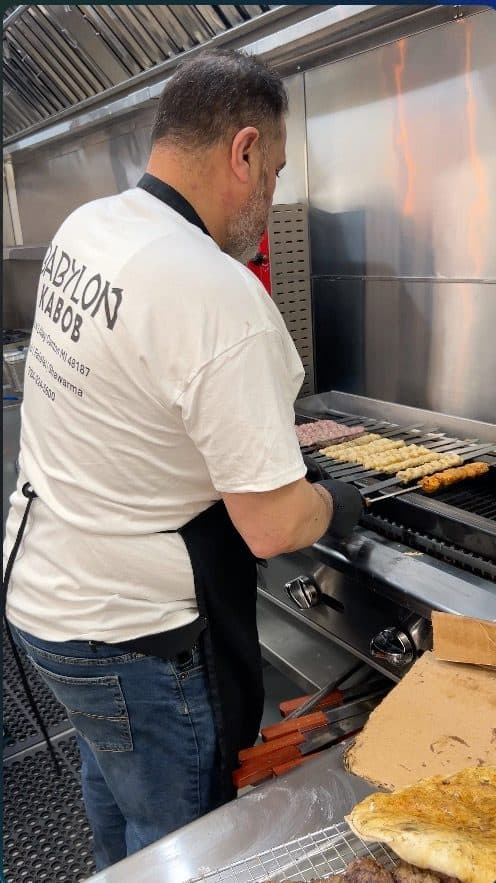 Mohammed Alshara turning kabob skewers at the charcoal grill