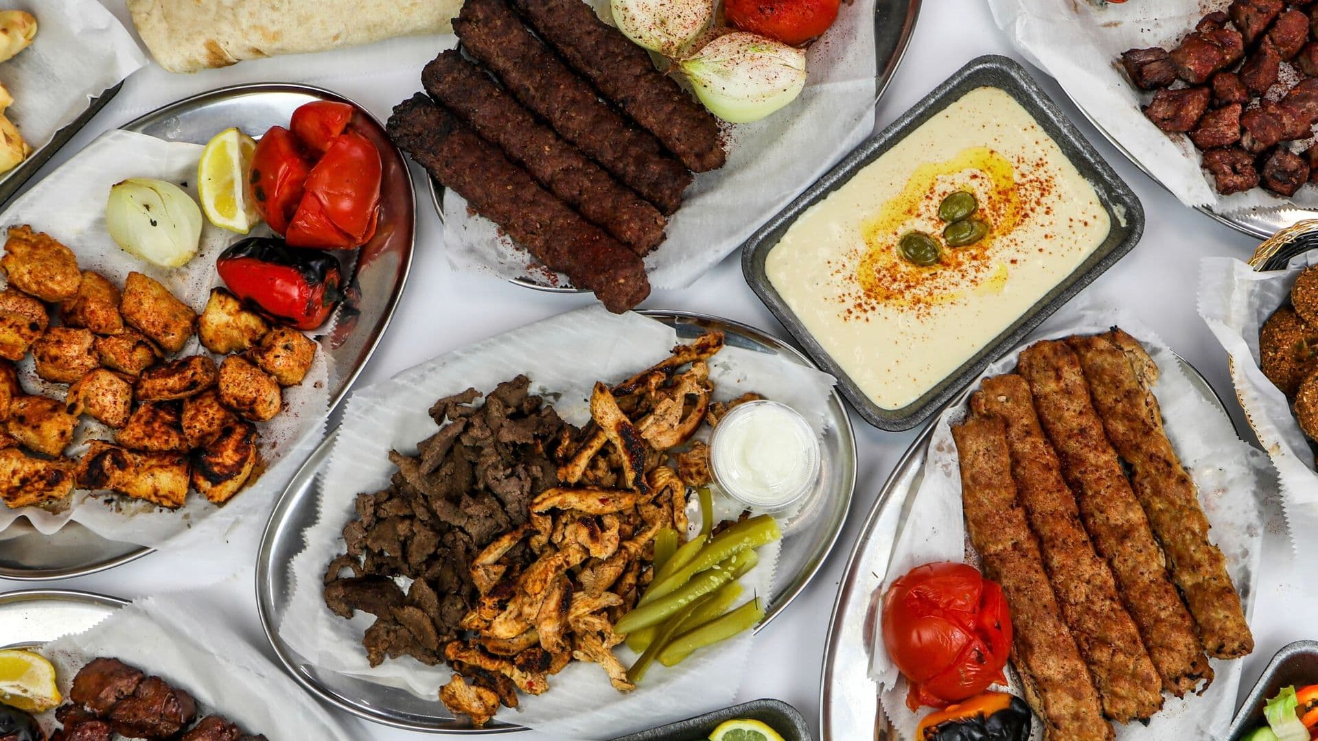 Overhead spread of skewers, shawarma and hummus